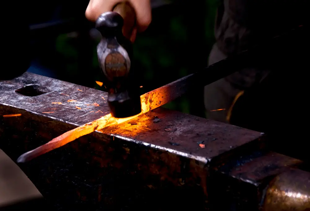 Beginner blacksmith working on an anvil.
