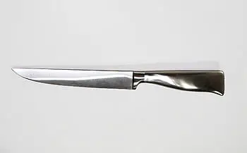 Chef's knife against a white surface.